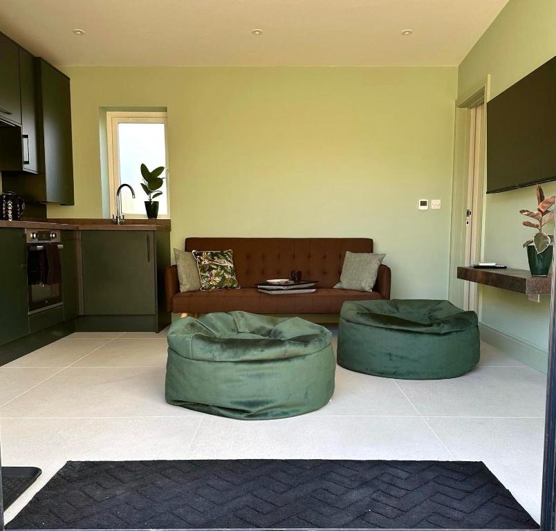 a living room with two green ottomans and a couch at White Oaks Sussex in Twineham