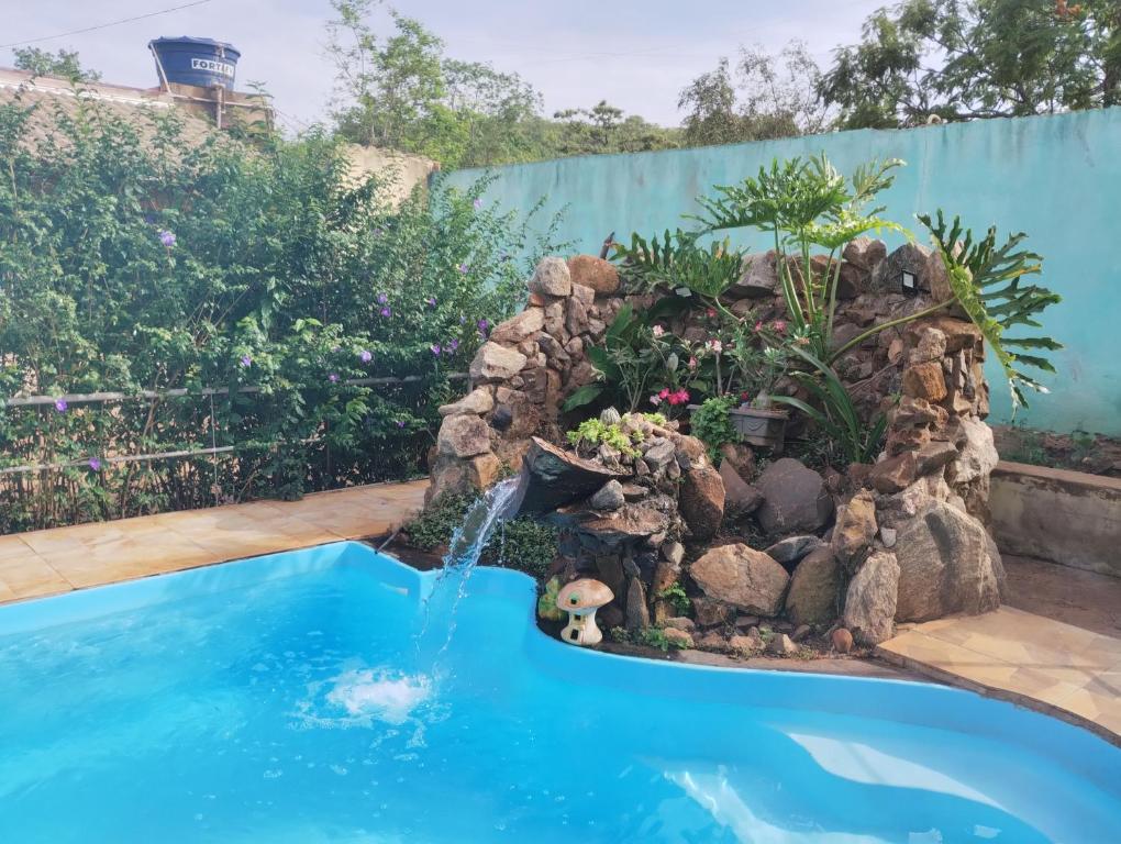 une petite piscine avec une cascade dans un jardin dans l'établissement Pousada Pôr do Sol, à Uberlândia