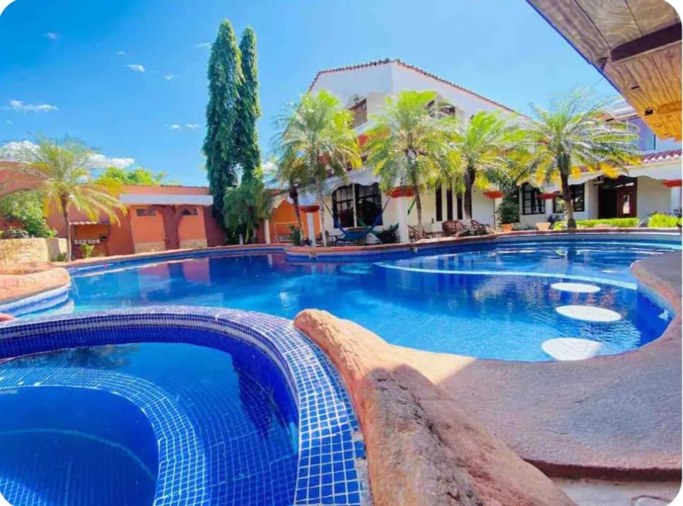 uma grande piscina num resort com palmeiras em Agradable y Lujosa casa de campo con piscina em Huité