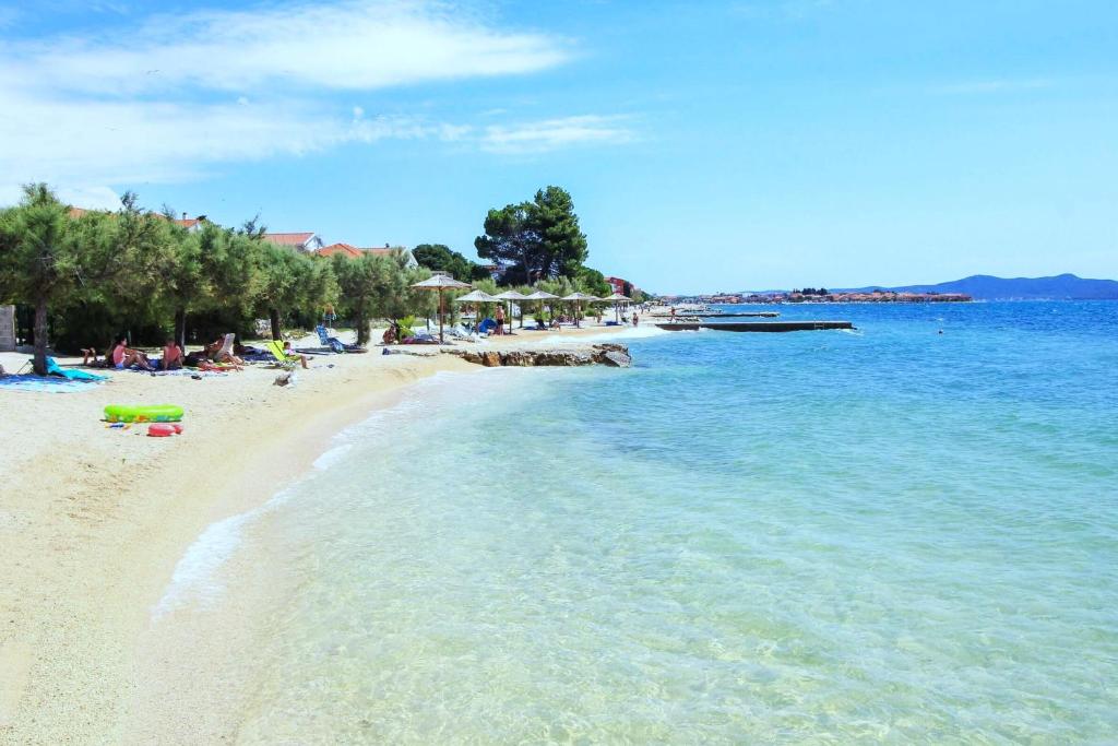a beach with people laying on the sand and the water at Holiday Home M & M in Bibinje
