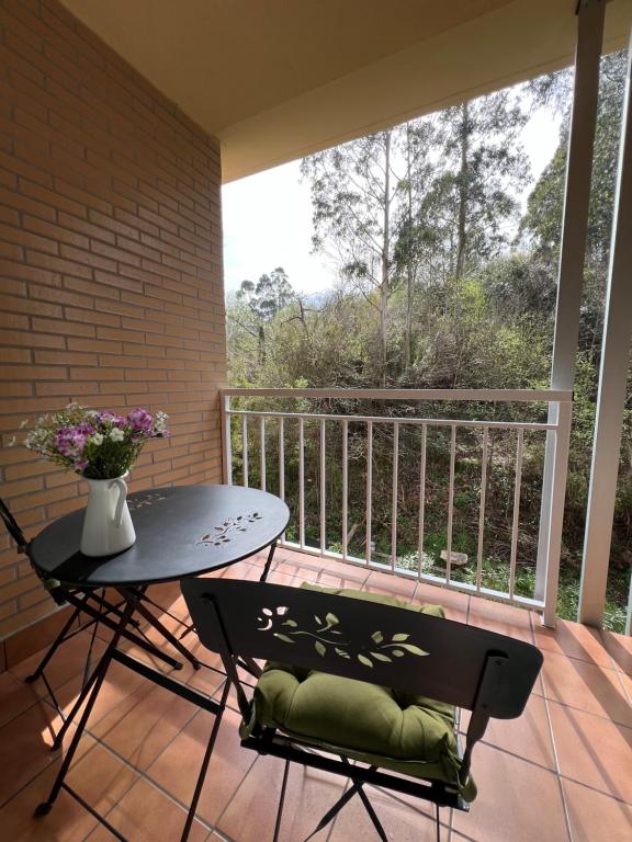 d'un balcon avec une table, des chaises et une fenêtre. dans l'établissement sands apartments, à Ribadesella
