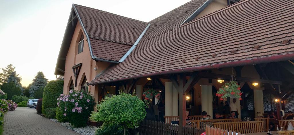 a building with a restaurant with flowers in front of it at Korona Panzió in Balatonberény