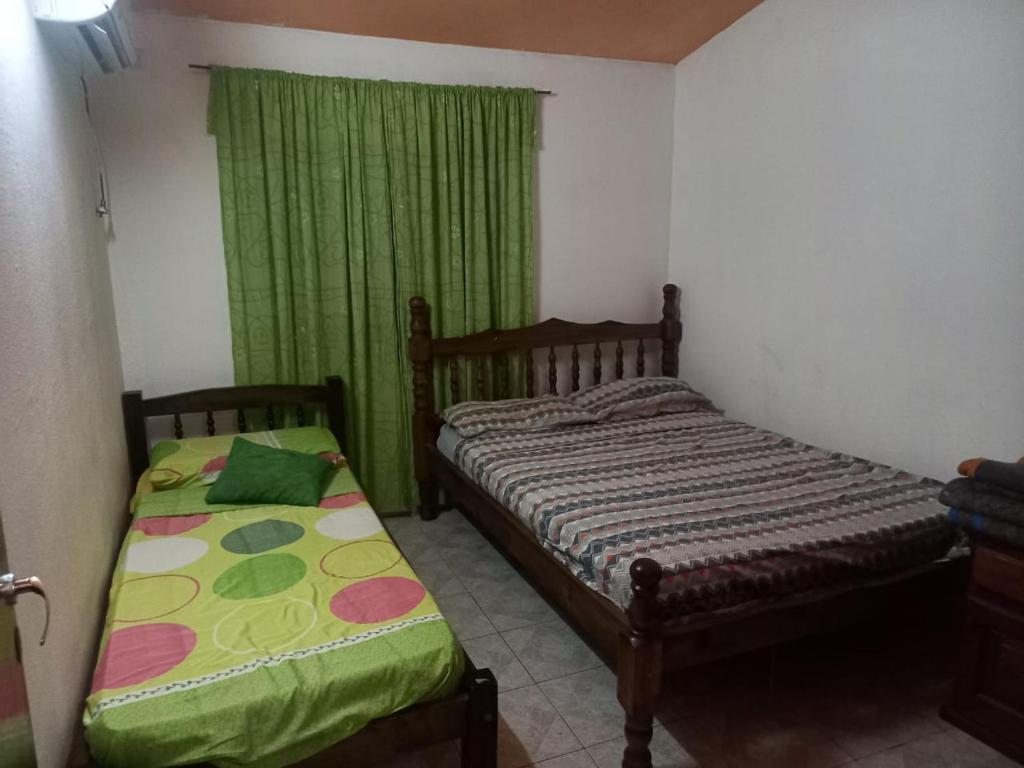 a bedroom with two beds and a window with green curtains at Flia Perez Derrache in Ituzaingó