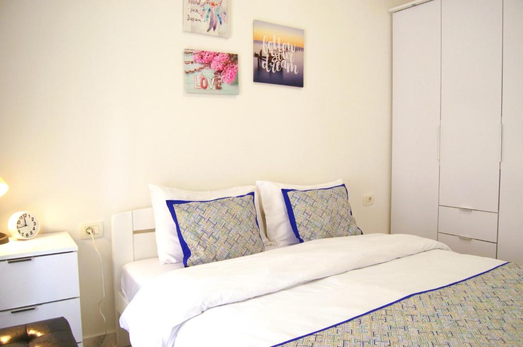 a bedroom with a white bed with blue pillows at Yeshill Apartments in Budva