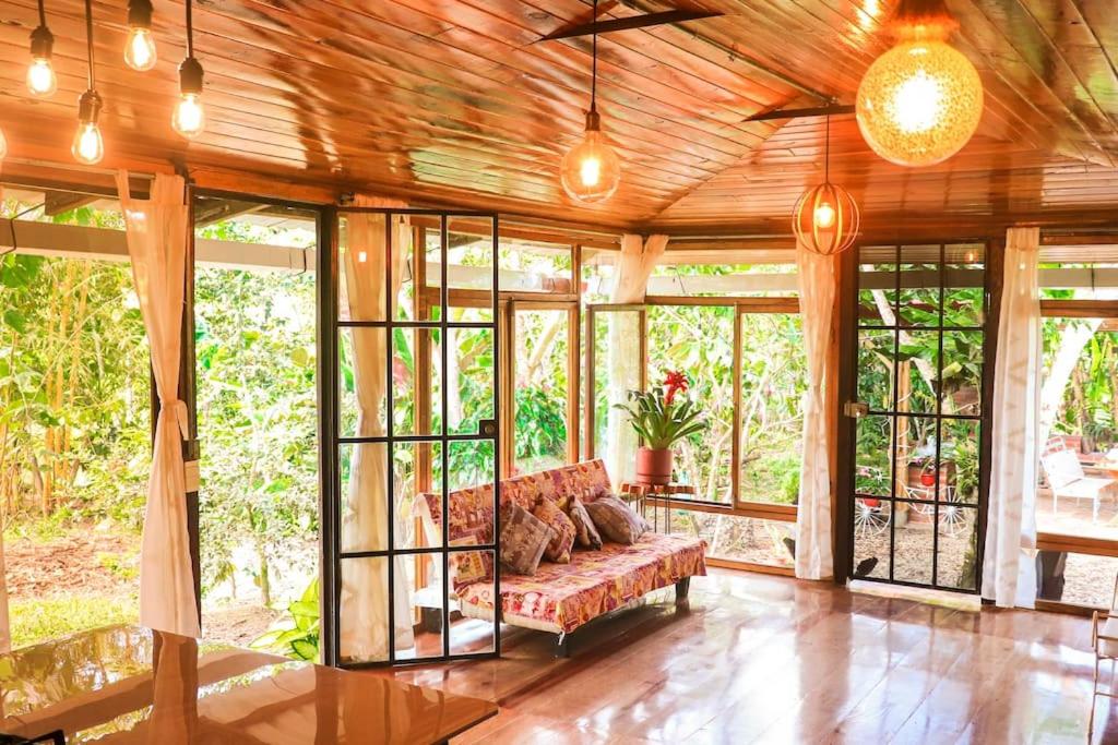 uma sala de estar com um sofá num quarto com janelas em Chalet Santacruz, Casa entera en la naturaleza em Nueva Loja