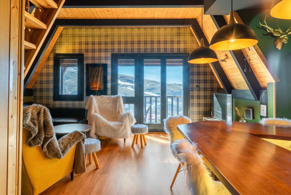 Una sala de estar con una mesa y sillas y una gran ventana. en PENTHOUSE IN THE CLOUDS & PARKING, en Sierra Nevada