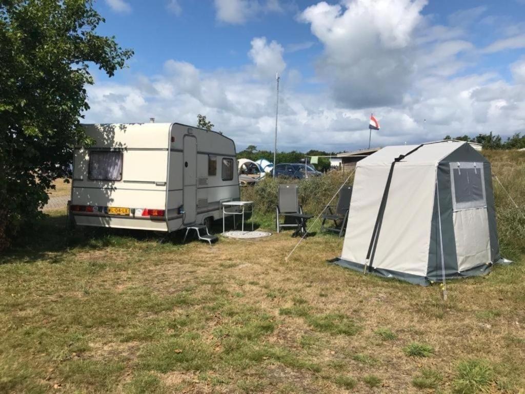 een rv en een tent in een veld bij Mobilheim für 2 Personen ca 10 qm in Buren, Friesland Ameland in Buren