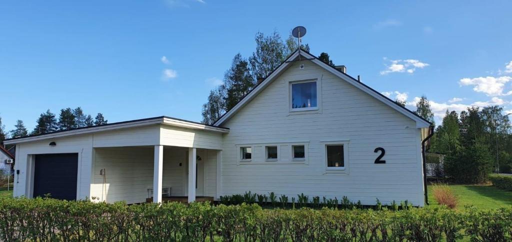 Ein weißes Haus mit der Nummer drauf. in der Unterkunft Villa Norrland, modern im skandinavischen Stil, mit Kamin, Garten und Saunafass in Vidsel