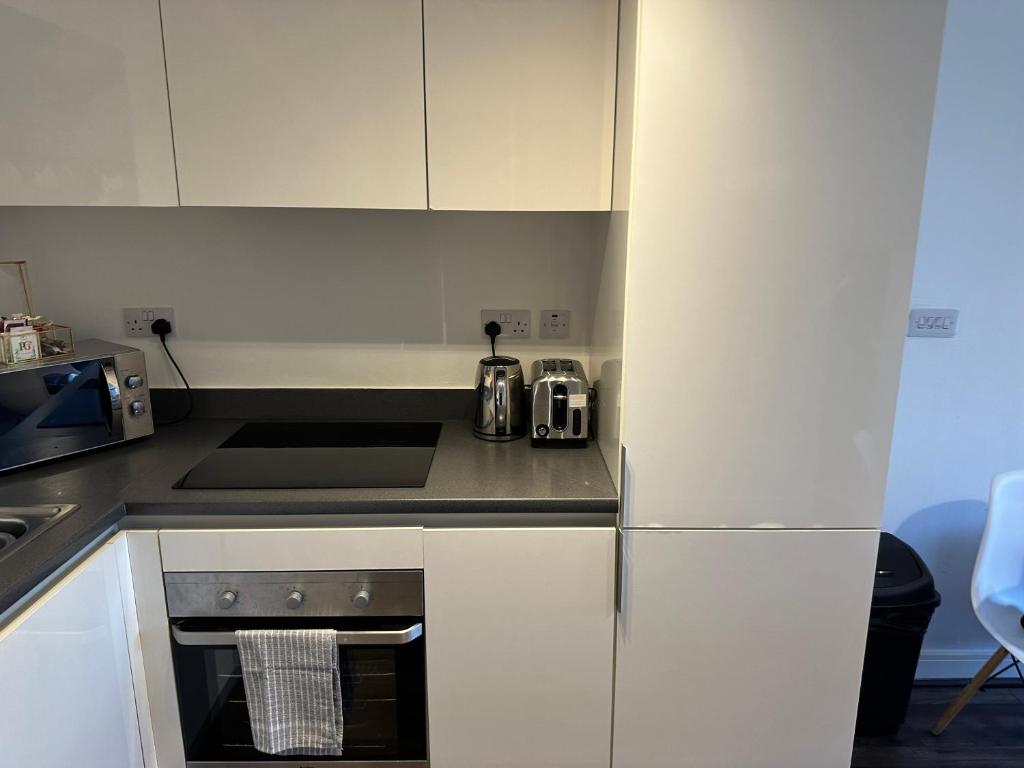 a kitchen with white cabinets and a stove top oven at The Landmark Brierley Hill in Dudley