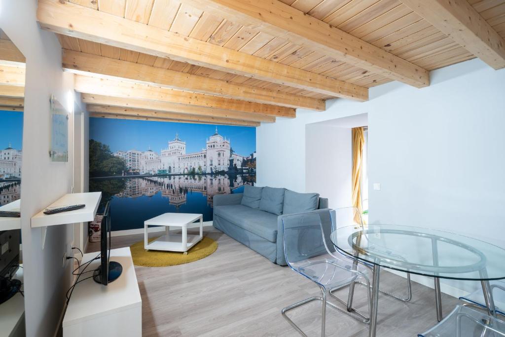 a living room with a blue couch and a glass table at Apartamentos GO - Leopoldo Cano Center in Valladolid