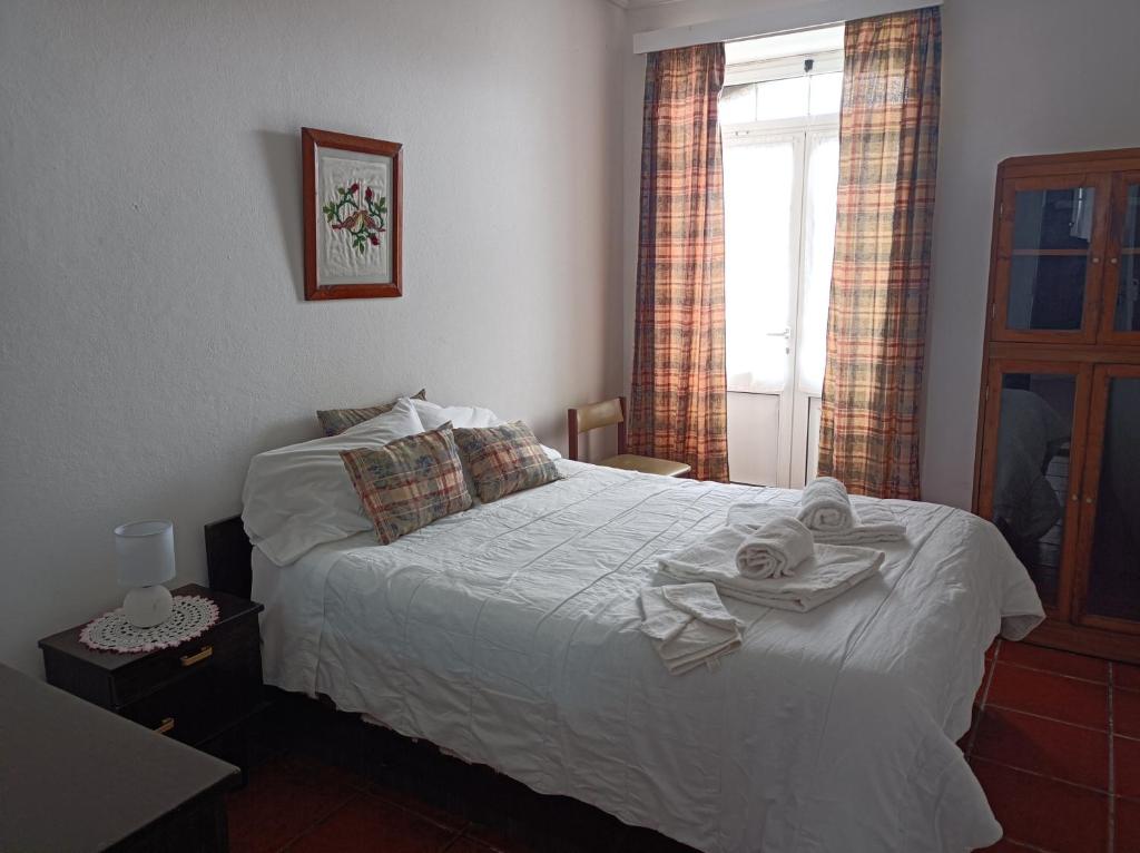 Rosário Guest House في لاجيس: غرفة نوم بسرير ابيض عليها مناشف