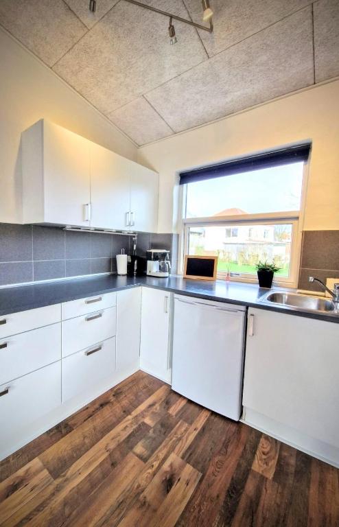 una cucina con armadietti bianchi e pavimenti in legno di Haus Fabjerg a Lemvig