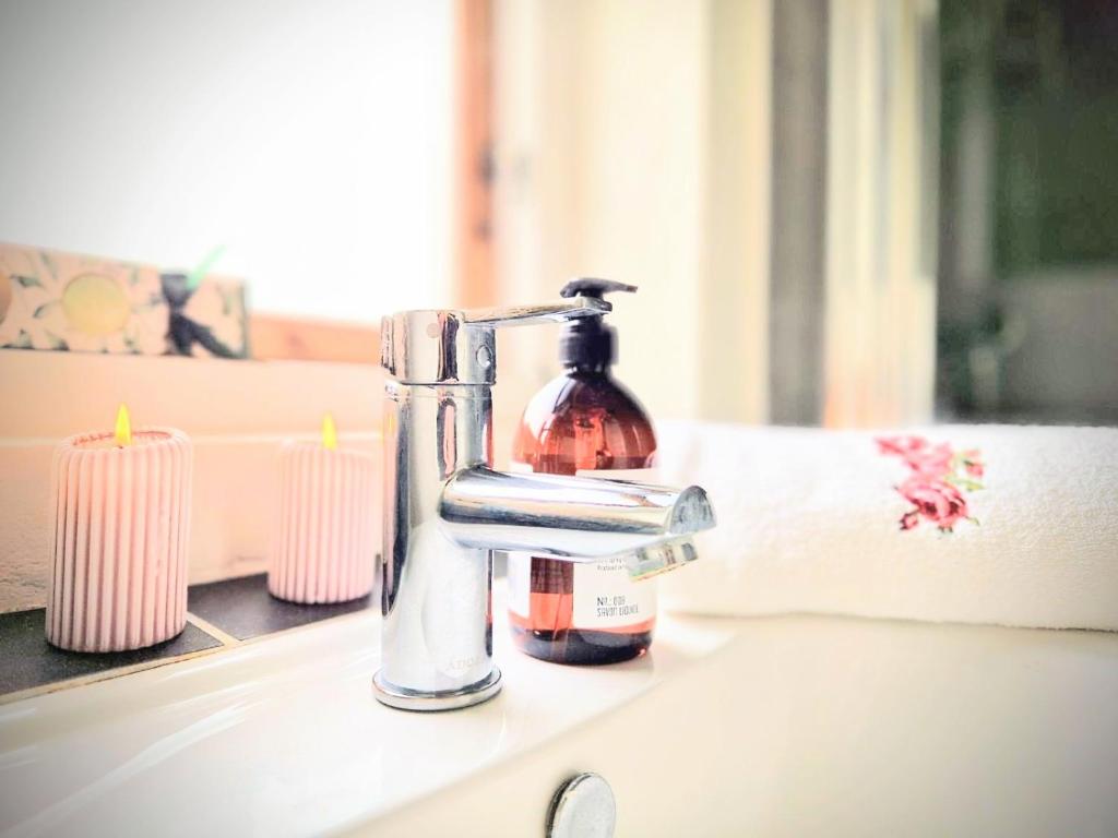 un dispenser di sapone seduto su un lavandino accanto alle candele di Haus Fabjerg a Lemvig