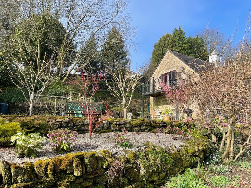 a garden in front of a house with a stone wall at The Cruck Barn, cosy rural escape near The Peak District in Matlock