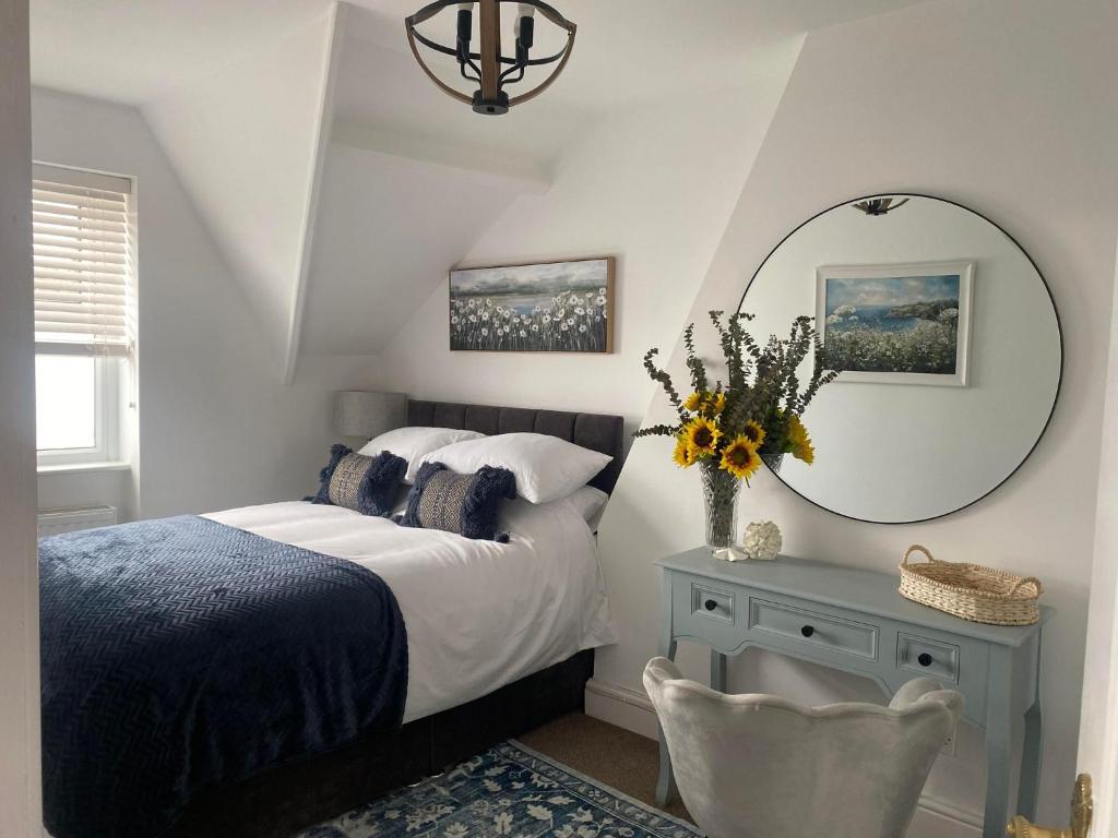 Un dormitorio con una cama con un espejo y una mesa. en The Penthouse at Percy House Pet Friendly 2 Bedroom Apartment in Porthcawl Sleeps 4 people Located in the town centre, en Porthcawl