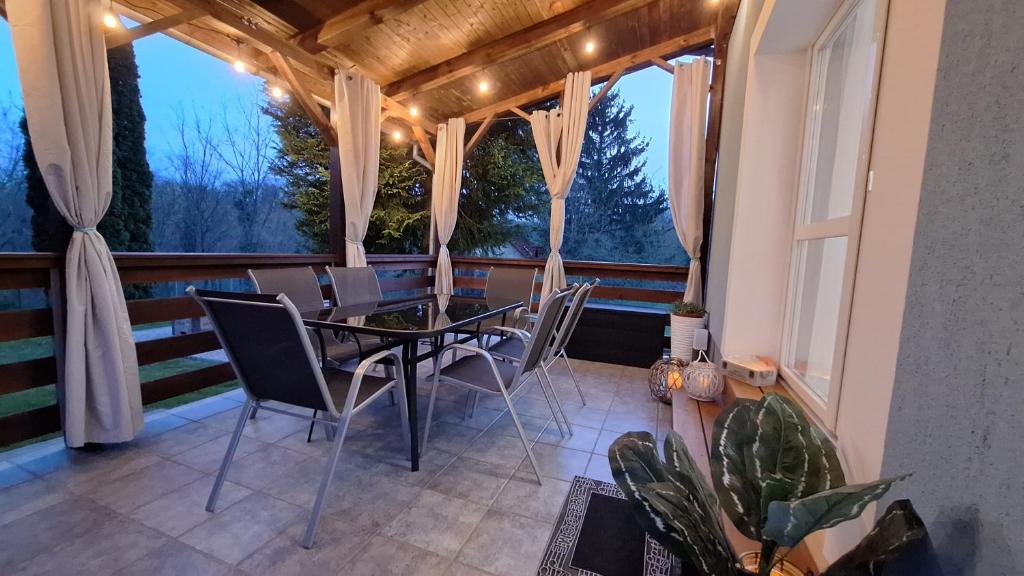 un porche cubierto con mesa y sillas en Jenny vendégház en Zalakaros