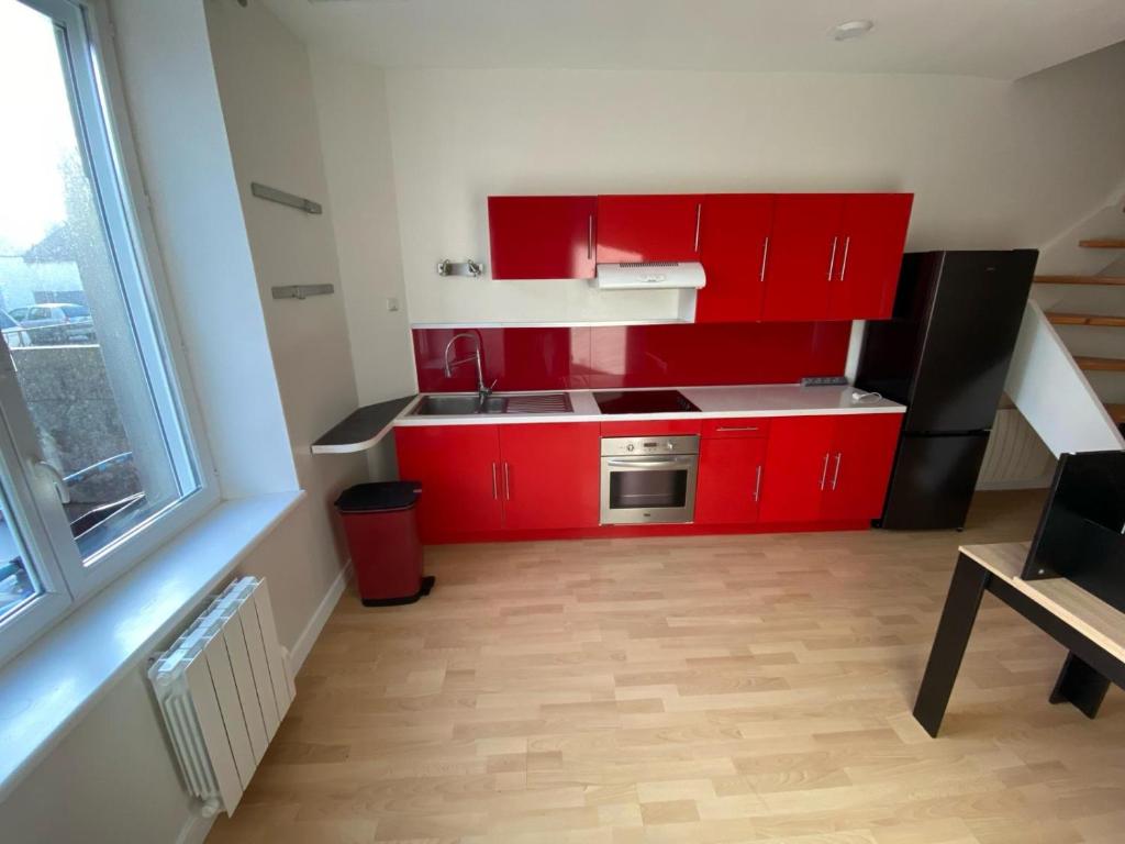 Elle comprend une petite cuisine avec des placards rouges et une fenêtre. dans l'établissement Duplex proche centre-ville, à Brest