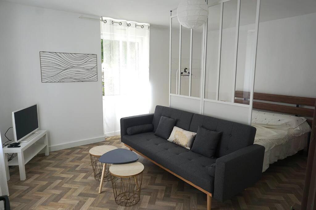 - un salon avec un canapé noir et un lit dans l'établissement Joli appartement 2 chambres au coeur du parc du Haut Jura, à Morez