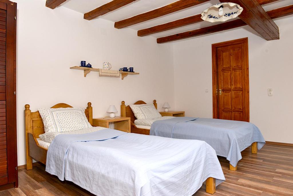 2 Betten in einem Zimmer mit weißen Wänden und Holzböden in der Unterkunft Rigófütty Vendégház in Tiszaalpár
