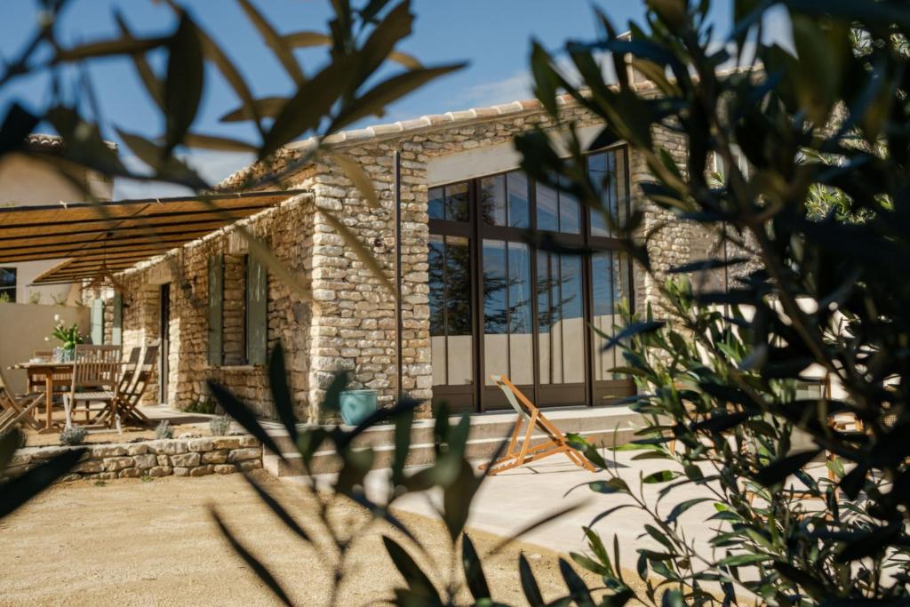 a stone house with glass doors and a patio at L'Atelier des Vignes in Saint-Pantaléon