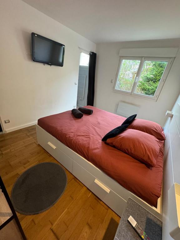 - une chambre avec un grand lit rouge et une télévision à écran plat dans l'établissement Beau studio plein centre ville, à Beauvais