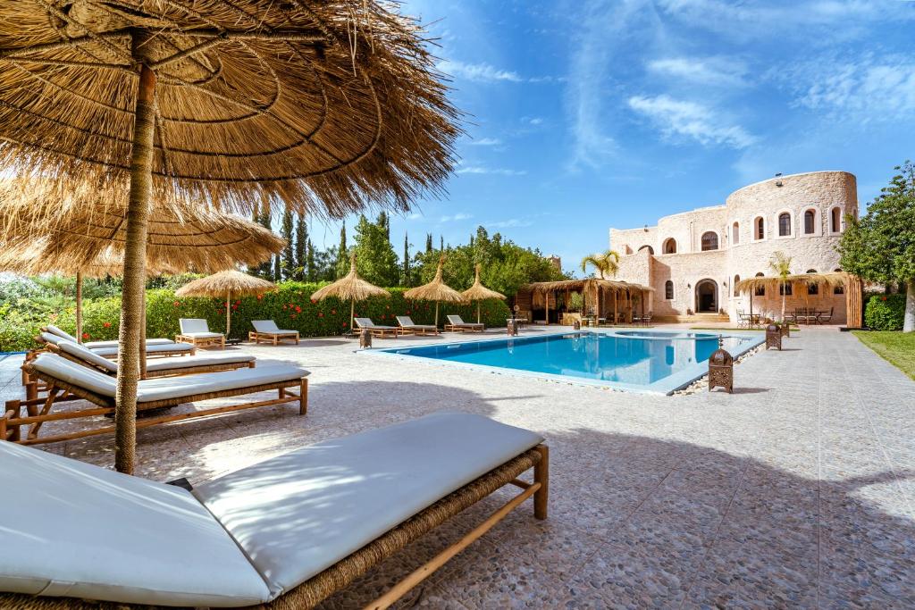 a resort with a swimming pool with chairs and an umbrella at RIAD YANITRI in Essaouira