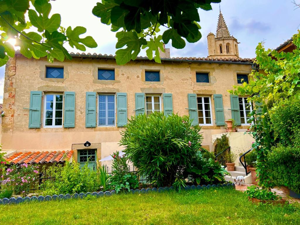 an old house with blue windows and a tower at Chez Luis et David in Avignonet-de-Lauragais