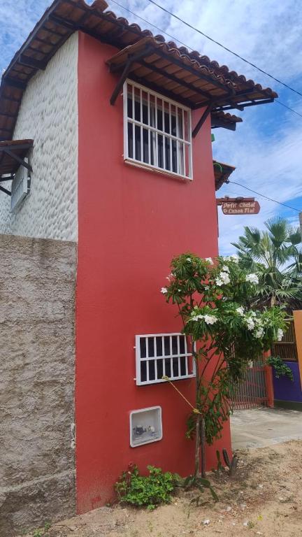 a red and white building with a window at Pousada PETIT CHALET Canoa Quebrada in Canoa Quebrada