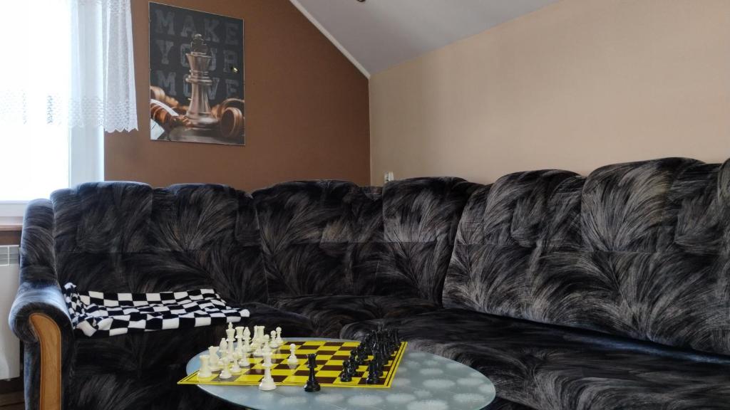 a black leather couch with a chess board on a table at Chess Apartament in Augustów