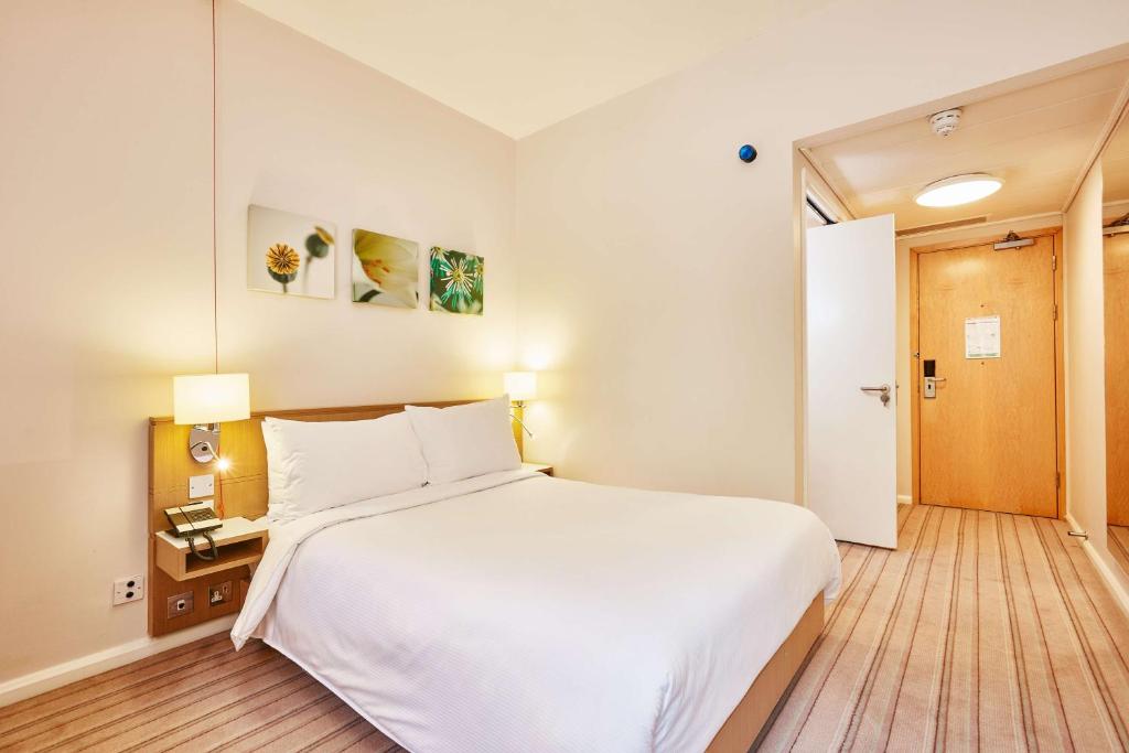 a bedroom with a large white bed and a wooden floor at Hilton Garden Inn Birmingham Brindley Place in Birmingham