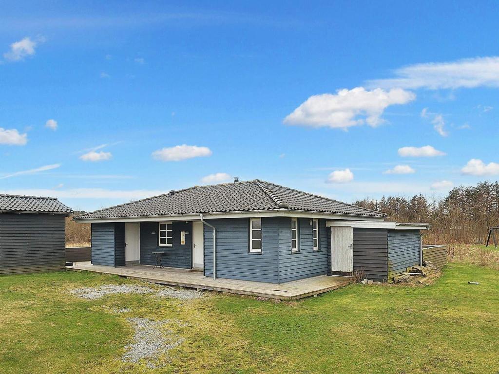 a blue house with a porch in a yard at Three-Bedroom Holiday home in Brovst 31 in Brovst