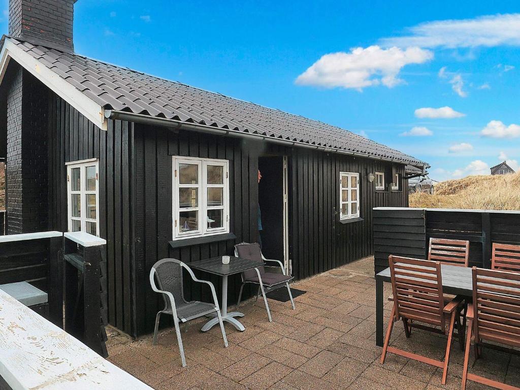 a small black building with a table and chairs at Holiday home Brovst XI in Brovst