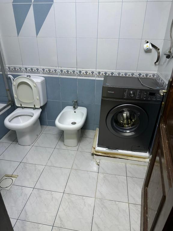 uma casa de banho com um WC e uma máquina de lavar roupa em شقه فخمه مفروشه بالكامل في اربد em Irbid
