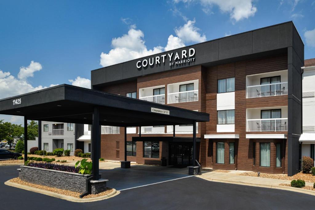 Courtyard by Marriott Charlotte Matthews في ماثيوز: اطلالة على مبنى مع موقف للسيارة