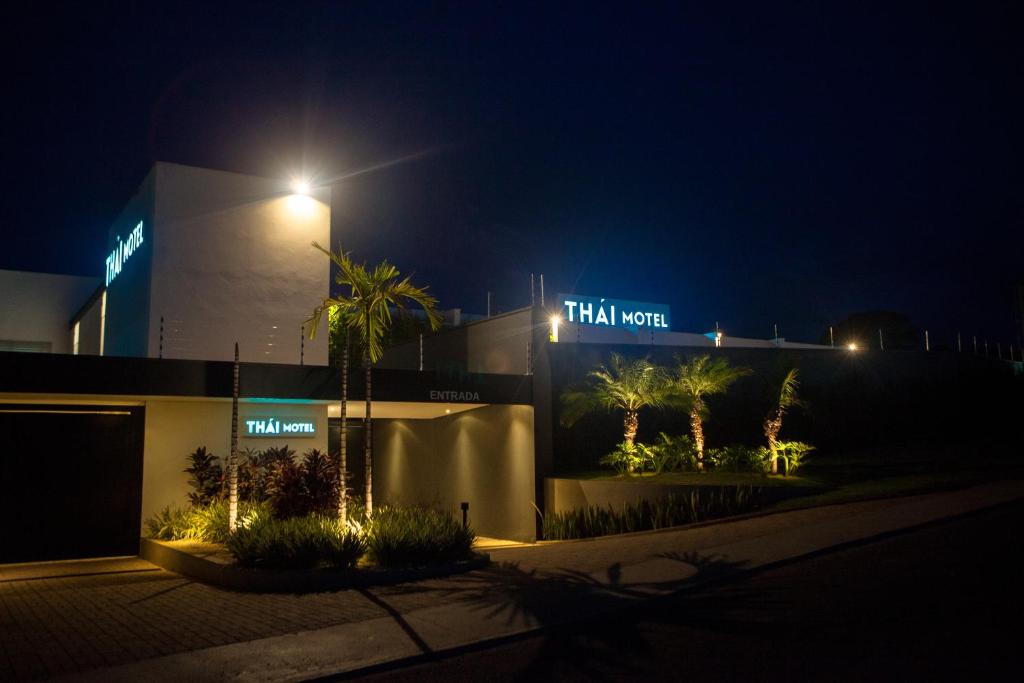 a building with a street light and palm trees at night at THÁI MOTEL in Mogi Guaçu