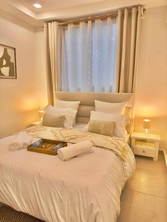 a bedroom with a large white bed with a window at Chez Maëlys in Douala