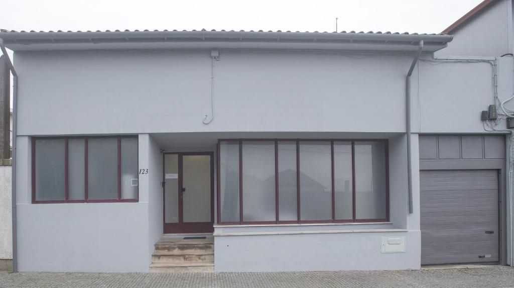 una casa bianca con finestre in vetro e un garage di Aerostay Hostel a Moreira