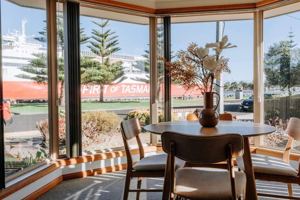 a dining room with a table and chairs in front of a window at Mama's on the Mersey in Devonport