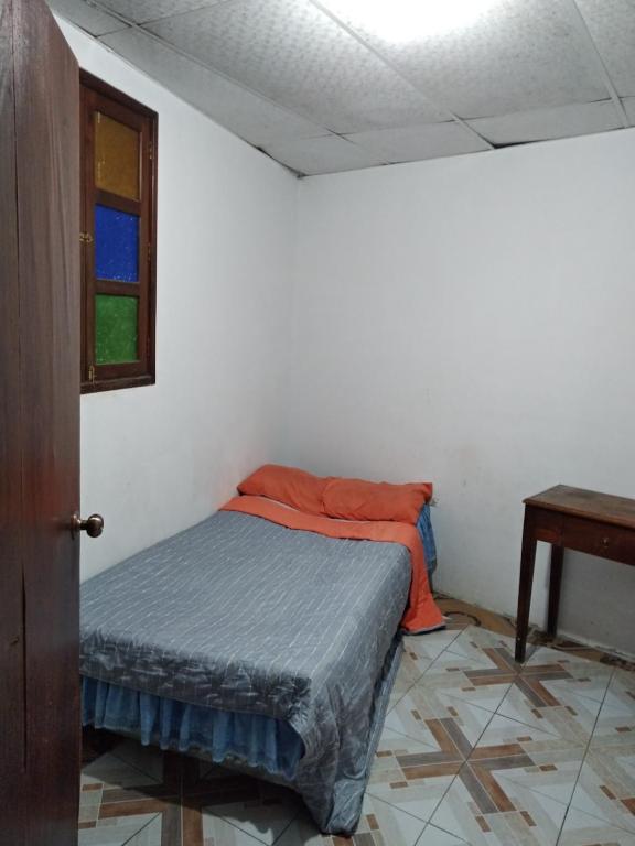 um quarto com uma cama com uma almofada laranja e uma mesa em Habitación en Antigua Guatemala em Guatemala