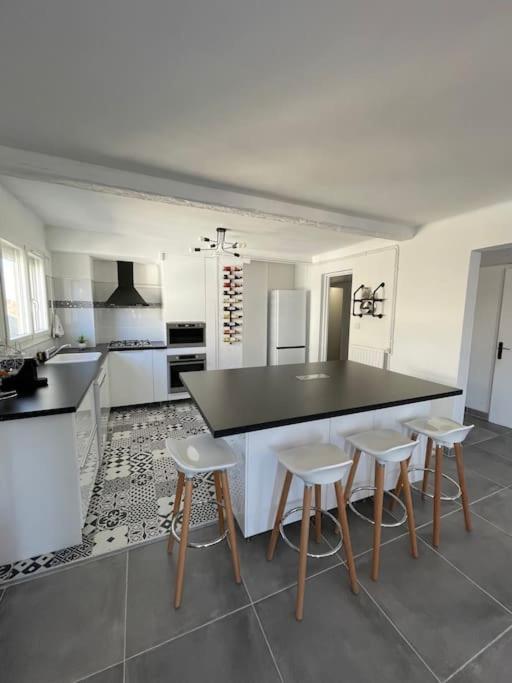 une cuisine avec un comptoir noir et quatre tabourets dans l'établissement Grand meublé touristique centre-ville Béziers, à Béziers