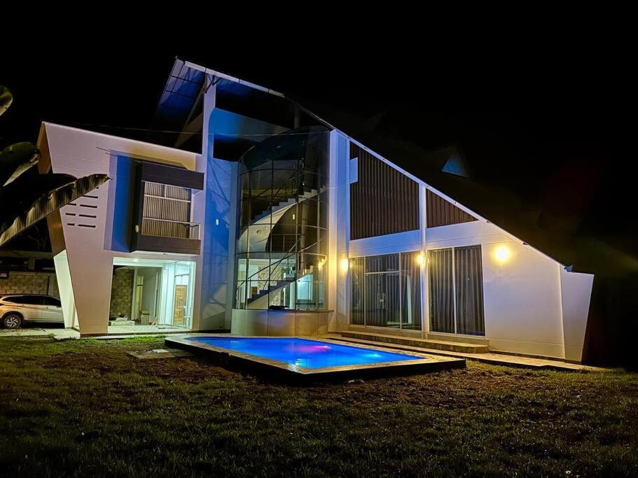 een huis met een blauw zwembad er 's nachts voor bij Casa de Alojamiento in La Merced