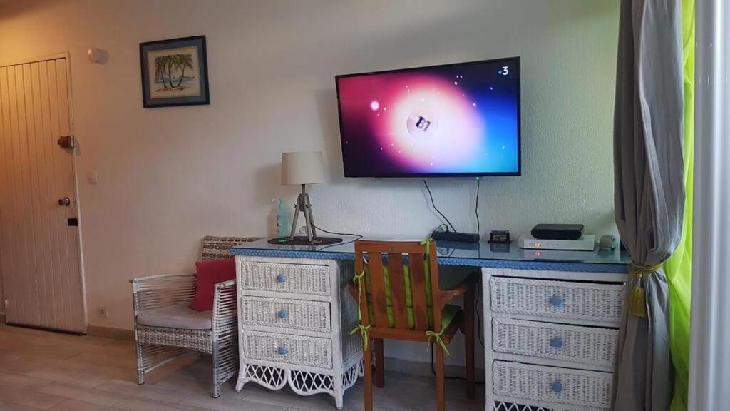 um quarto com uma secretária e uma televisão na parede em Village Creole - 3ILETS em Les Trois-Îlets