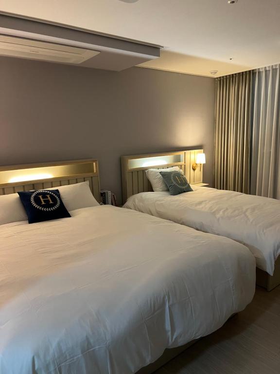 two beds in a hotel room with white sheets at 호야스테이 Hoya stay in Yeosu