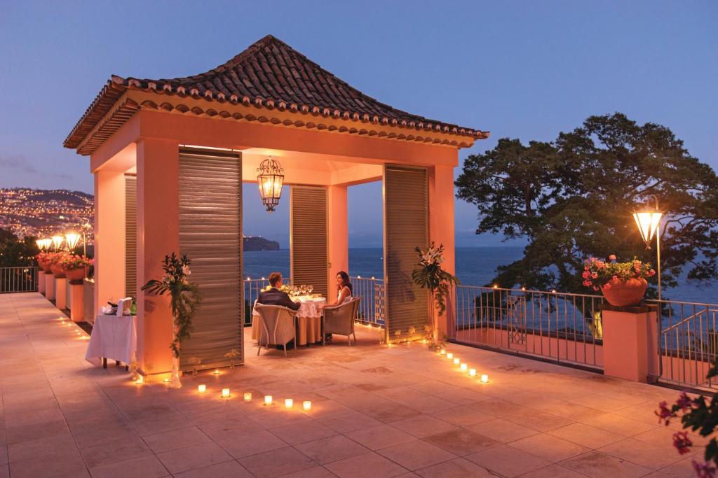 a gazebo with people sitting at tables on a patio at Reid's Palace, A Belmond Hotel, Madeira in Funchal