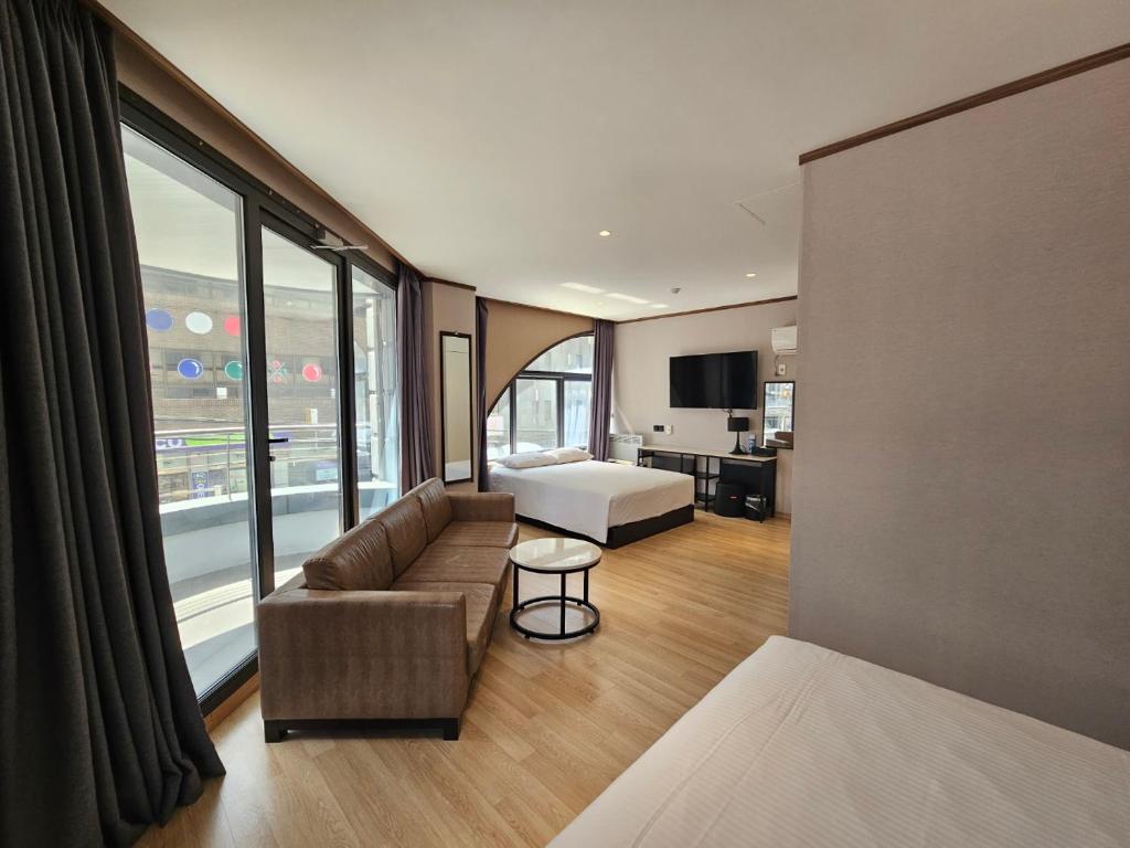 a room with a bed and a couch and a bed and a room with at Sunland Hotel in Jeju