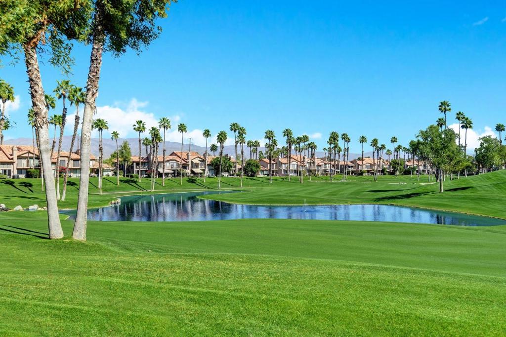 a golf course with palm trees and a pond at VB944 - Triple Fairway View - Palm Valley CC in Palm Desert