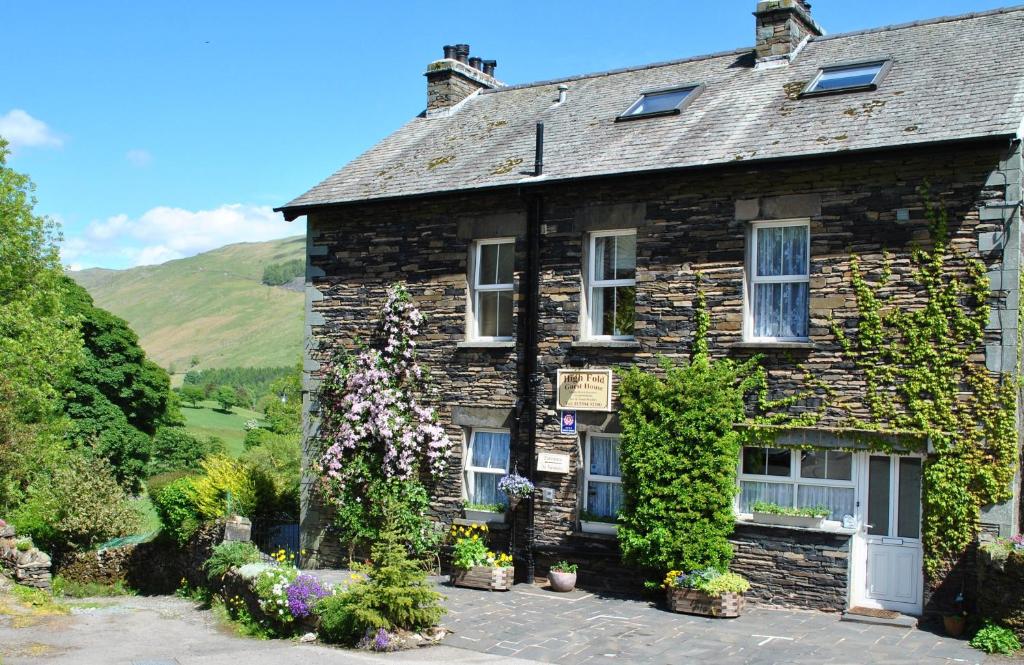 an old stone house with flowers in front of it at High Fold Guest House in Troutbeck