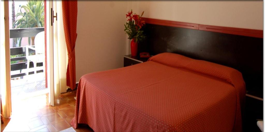 a bedroom with a bed with an orange blanket at Hotel La Playa in Alghero