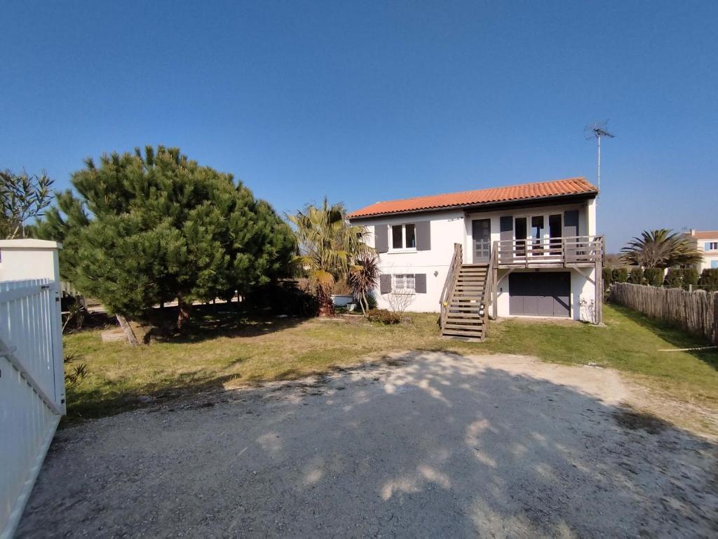 une maison blanche avec une clôture et une cour dans l'établissement Grande maison avec jardin, proche plage, 4 chambres, terrasse, pour 8 personnes - Île d'Oléron - FR-1-778-22, à Grand-Village-Plage