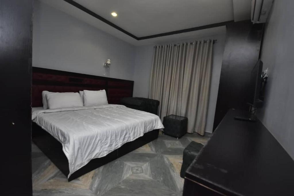 um quarto com uma cama e uma televisão de ecrã plano em La Vista Imperial Hotel em Enugu